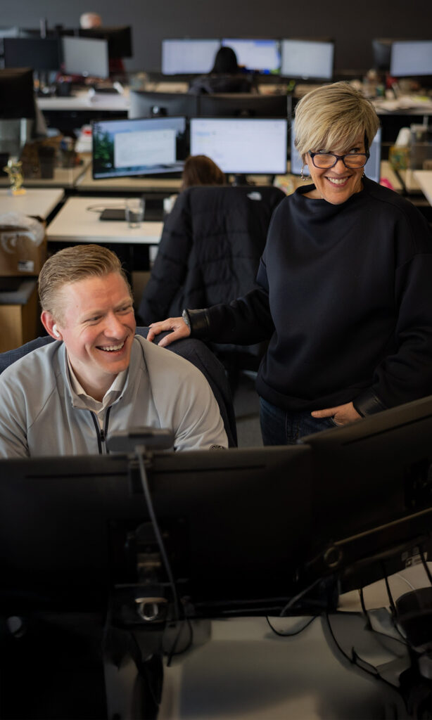 Two Skender team members collaborating over a computer workstation.