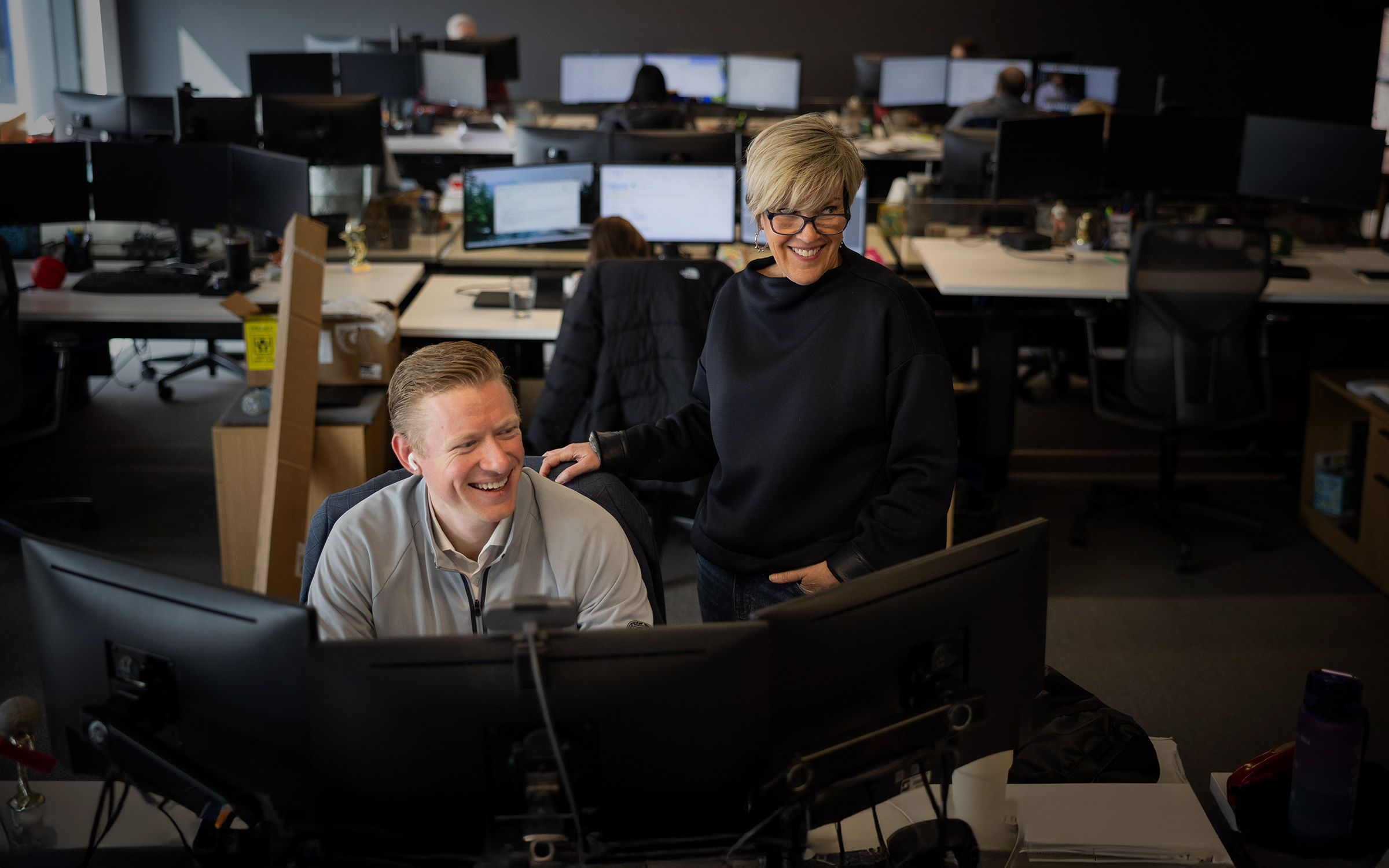 Two Skender team members collaborating over a computer workstation.